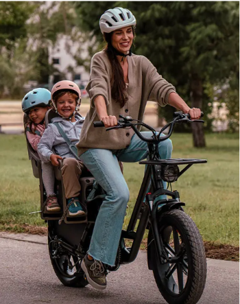A mom cycling with her two kids on a cargo e-bike and enjoying the atmosphere