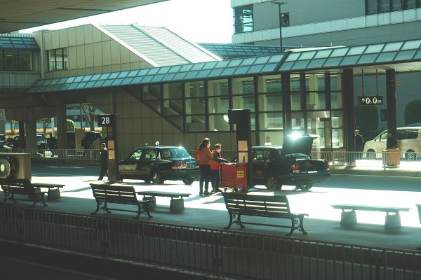 A station with taxis parked and people standing outside