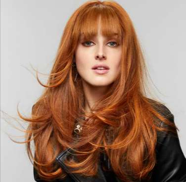 A red-haired woman with long curled hair after using the Bumble and bumble colour maintenance collection