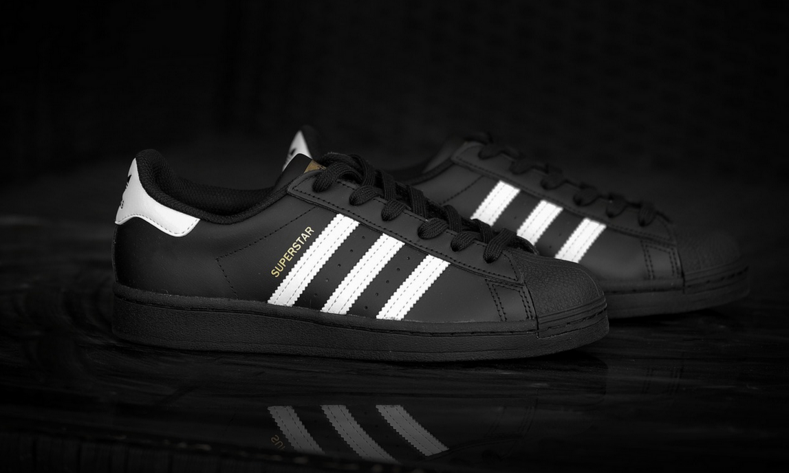 Zwei schwarze Adidas Schuhe mit drei weißen Streifen