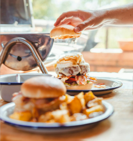 Crop man putting half of bun on burger