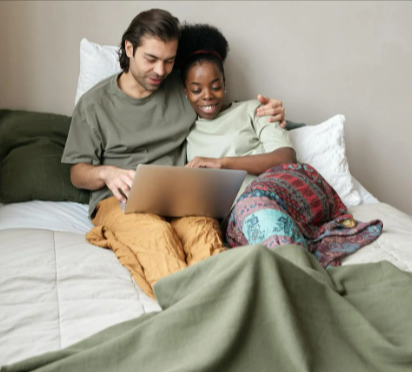 Couple with a laptop in bed with the DreamCloud hybrid mattress