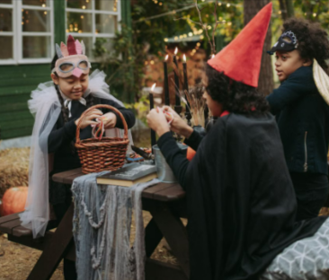 A group of children in costumes celebrating Halloween at a picnic table.