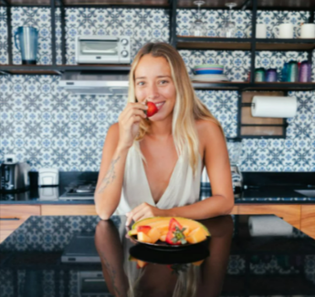 A woman eating a strawberry in a kitchen with a discounted blue patterned Custom Splashbacks