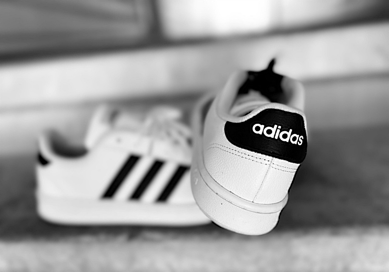 zapatos de adidas blancos sobre fondo blanco y rayas negras