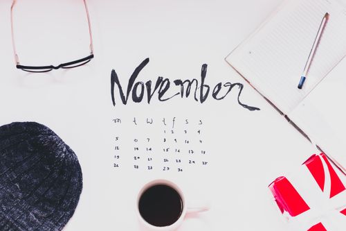 The November calendar surrounded by stationery and glasses