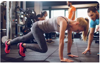 A woman in the gym being assisted by an instructor