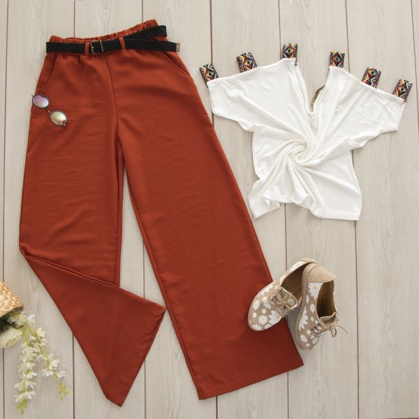 Wide leg pants, a white short sleeve top, beige and floral shoes, and sun glasses on a wooden floor