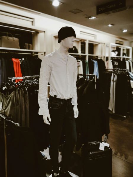 A mannequin dressed in a white shirt, black jeans, and a black beanie hat in a clothing store
