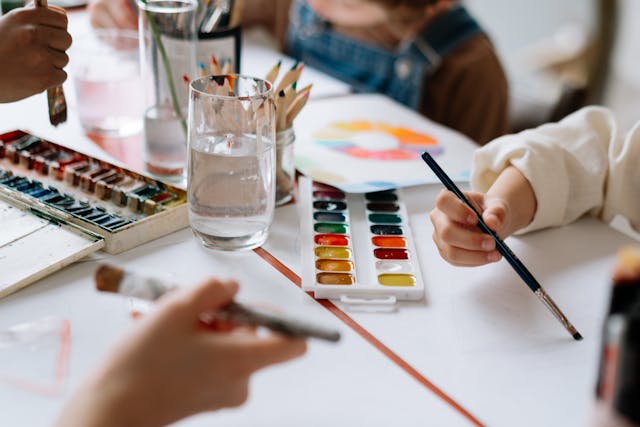 Winter school holiday activities: Children holding paintbrushes and painting on paper