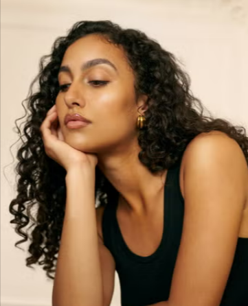 A woman showing her curly hair that is maintained by using the Christophe Robin curly hair regimen