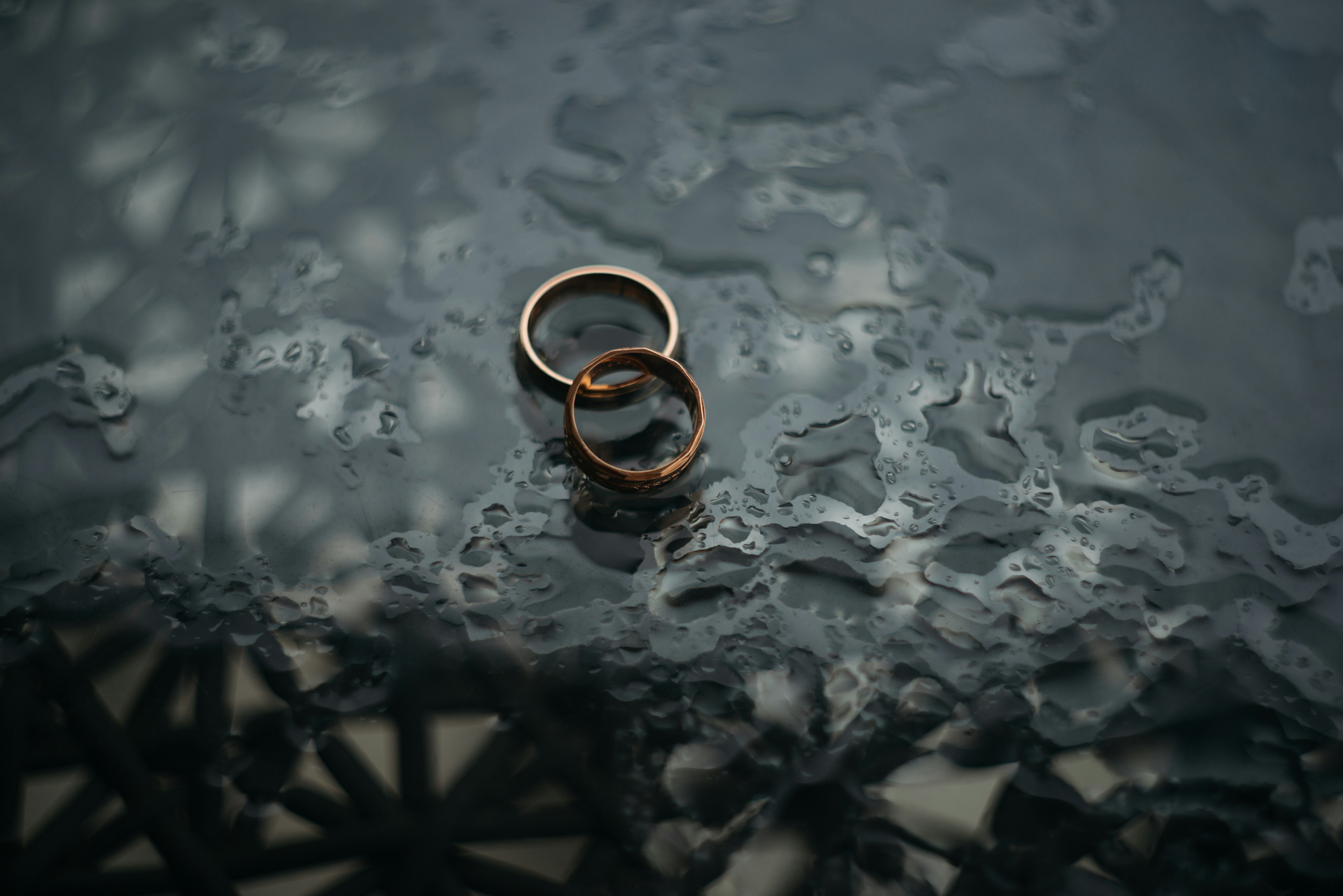 Two wedding bands are placed on a dark wooden table