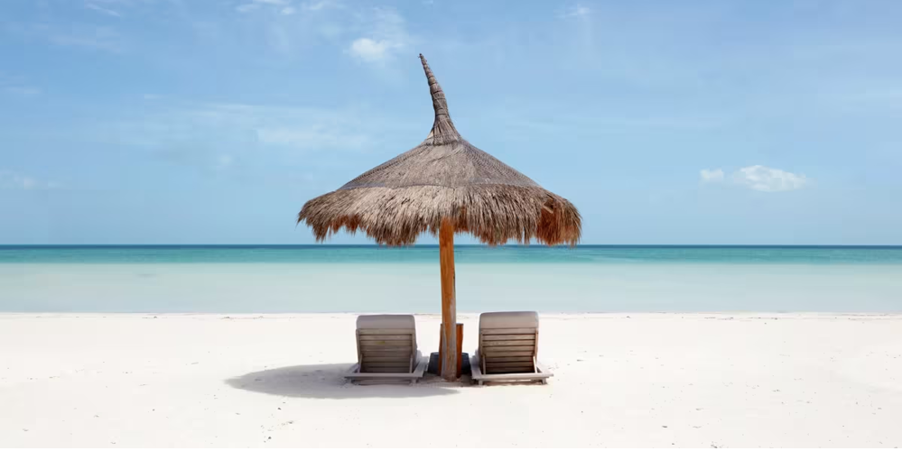 Ein Strand mit zwei Holzliegen und einer Holzschirmüberdachung