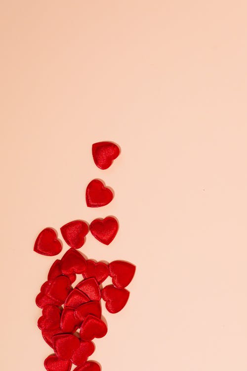 A bunch of red hearts laying on a pink surface