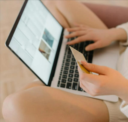 Person using a laptop and holding a credit card