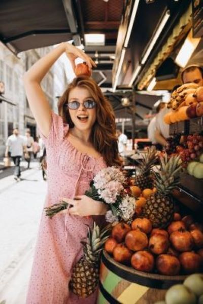 A young woman in a pink dress and holding flowers, celebrating savings after using a Singles Day voucher code