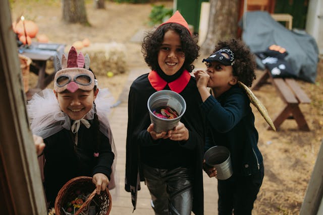 Three children dressed in Halloween costumes who are trick-or-treating.