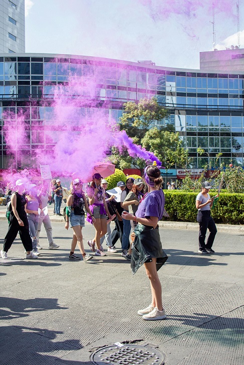 image showing a group of women, with one spraying out purple fog