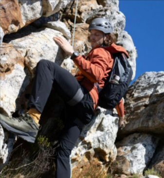 A man hiking in the mountains while wearing a Dare 2b Men's Torrek III Waterproof Jacket in the colour Arabian spice