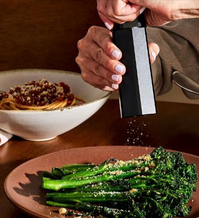 The HEXCLAD HexMill tabletop salt & pepper grinder set with a plate of brocolini and spaghetti