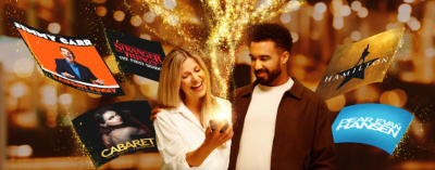 A man and a woman standing, looking into a phone and smiling