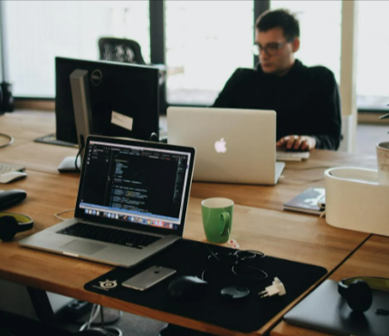 Man in black shirt sits behind desk with computers sourced from Currys Business