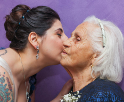Woman kissing woman with boutonniere on her chest
