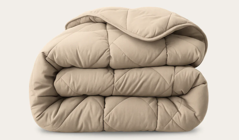 Eine zusammengefaltete Bettdecke in Beige-Farbe von HappyBed