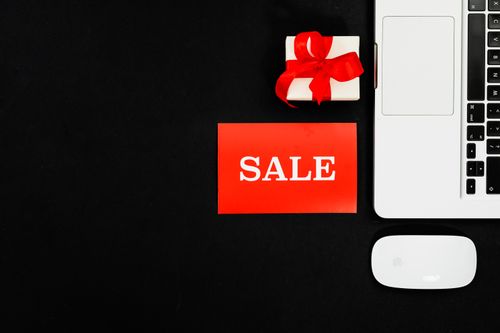 A latop, present and computer mouse next to a red "Sale" sign