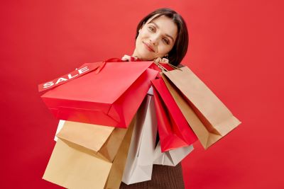 A lady carrying a bunch of shopping bags with a red "Sale" sticker in a red background