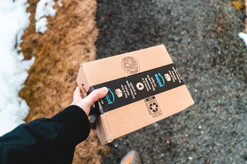 A person holding an Amazon delivery box that they saved on during Amazon Prime Day