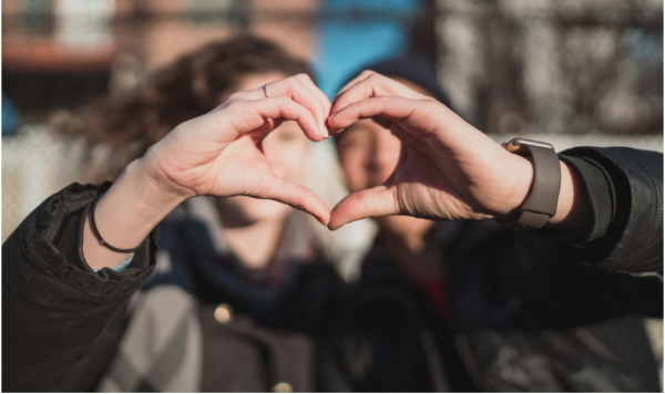 A man and a woman forming a heart shape with their fingers