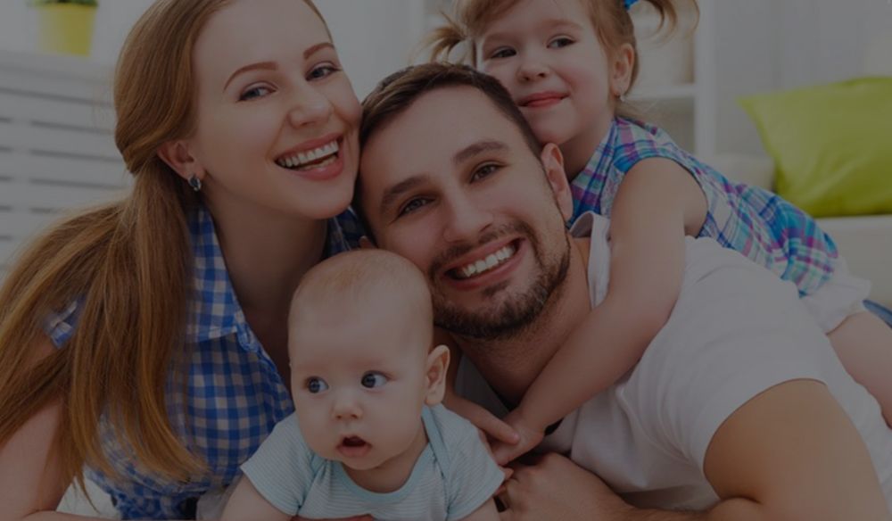 a family of four, mom ,dad, boy and girl smiling as they are covered by Nova Direct
