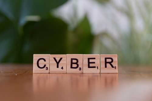 The words "Cyber" spelling out in wooden blocks on top of a wooden surface