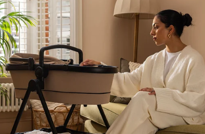 Woman sitting beside a modern baby bassinet