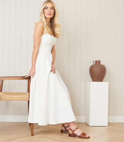 A lady wearing a white dress and brown Carl Scarpa sandals