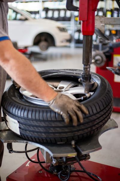 A mechanic fitting a tyre onto a wheel rim in a workshop