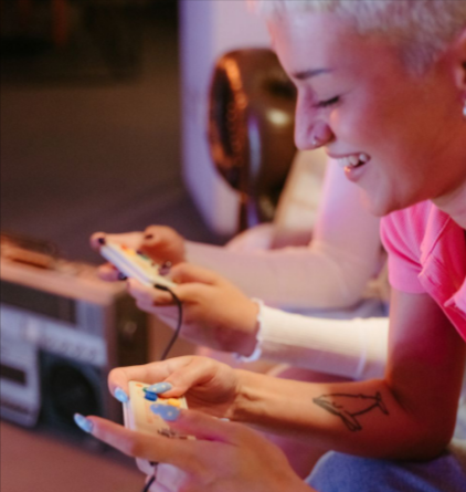 Laughing woman with short hair and tattoos enjoying a video game online with her G2A account indoors.