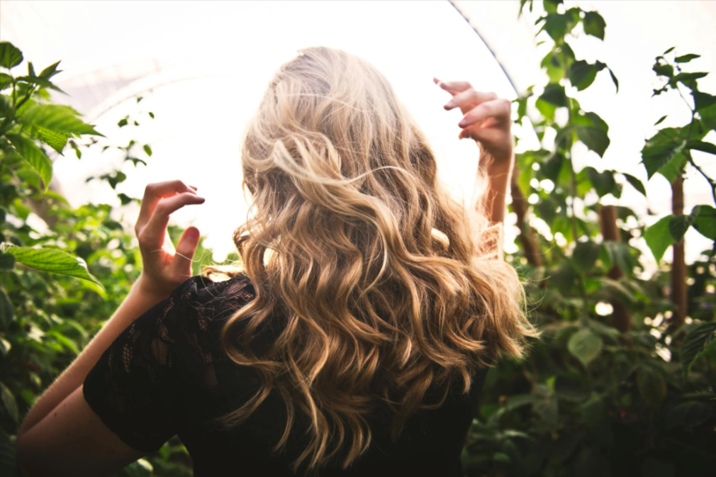 donna che cammina all'aperto mentre si controlla i capelli tenuti bene con un prodotto comprato in offerta con un codice sconto CRLab