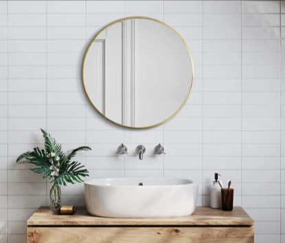 A round bathroom mirror on the wall and a white sink on a wooden bathroom cabinet