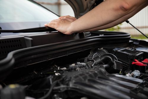 A person reparing a car engine after reading a manual they saved on with a Haynes coupon code