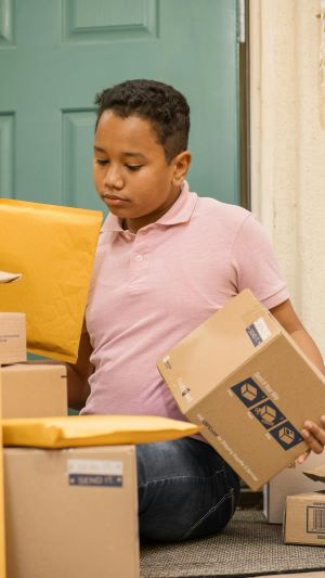 A young boy sitting on the floor with a box in one hand and a sealed envelope in the other