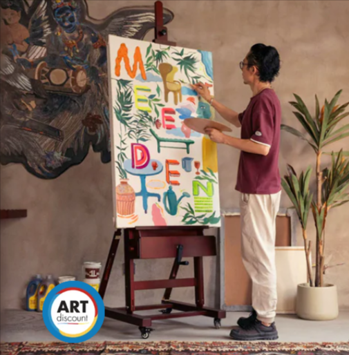 A man painting on a canvas which is propped up on an easel