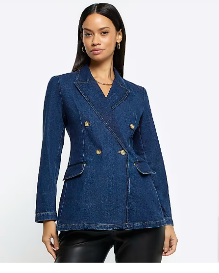A lady with straight black hair wearing a blue fitted denim blazer and leather tight pants