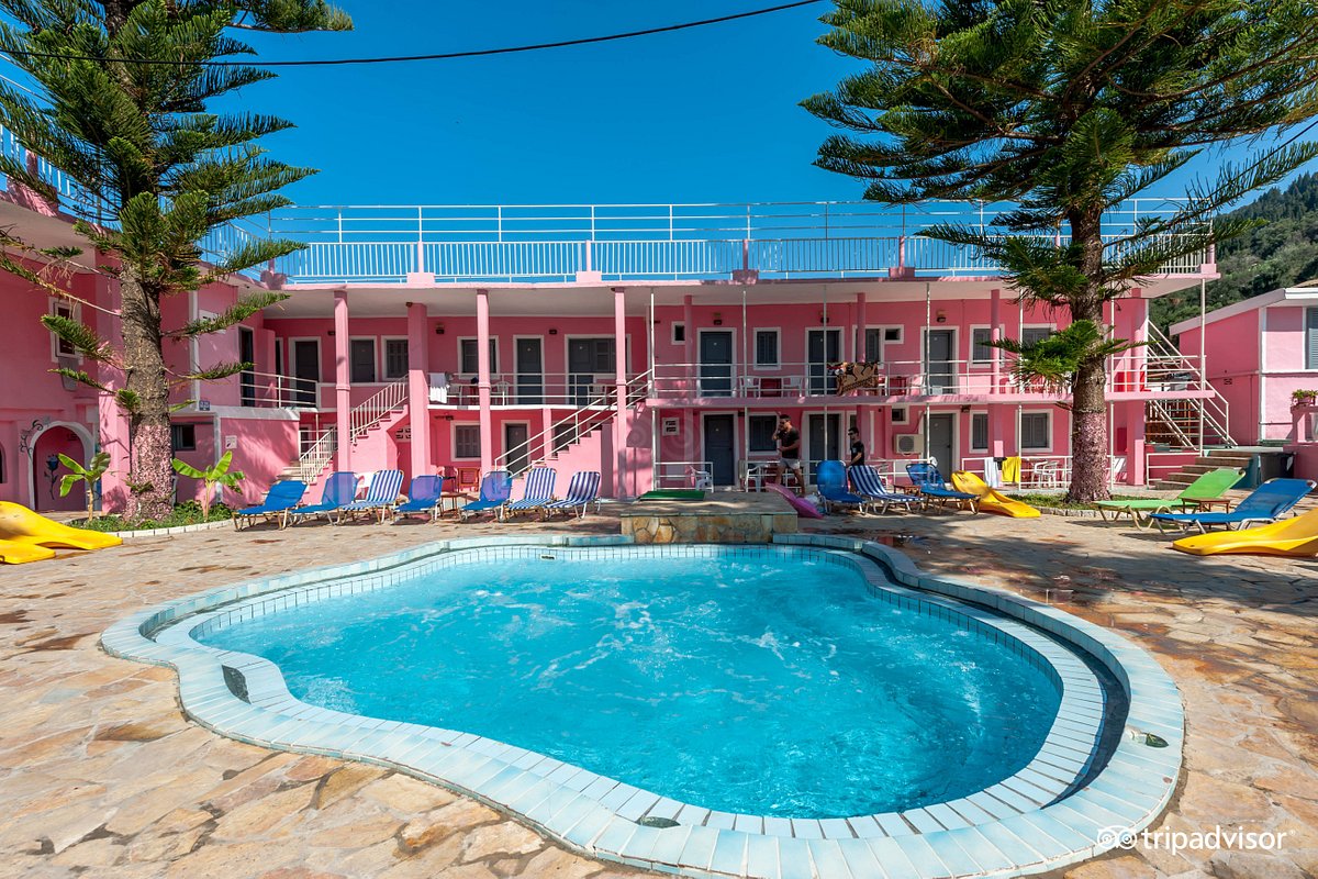 Hostel ve hostel havuzu arasında ayakta duran genç adam telefon ile konuşuyor