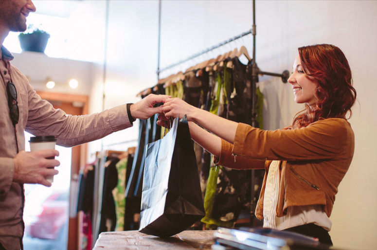 Smiling owner giving the customer his shopping bag with the purchases he made