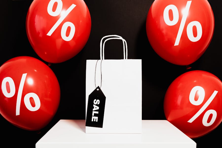 Red ballons with percentage signs on it and a sale gift bag in the middle