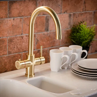 A Fahren gold filter tap with white cups and plates in a farmhouse kitchen