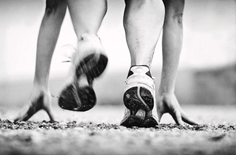Black and white image with an athlete getting ready to take off for a race with their hands on the ground