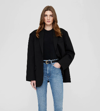 A Woman wearing a black oversized blazer and a blue jean with a belt